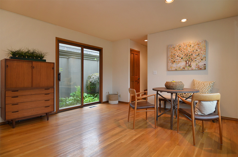 Foto di una grande sala da pranzo aperta verso la cucina minimal con pareti bianche e pavimento in legno massello medio