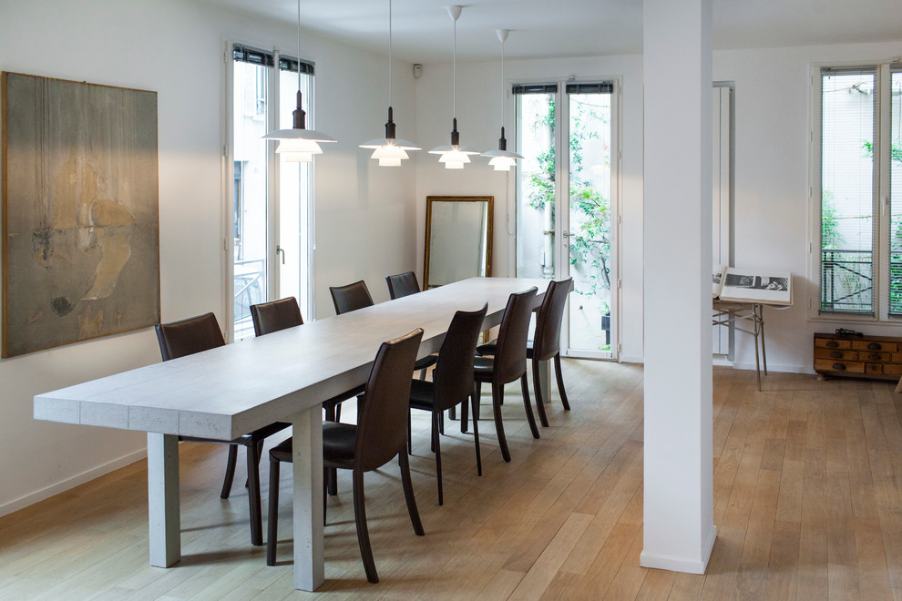Immagine di una sala da pranzo aperta verso il soggiorno minimal di medie dimensioni con pareti bianche, parquet chiaro e nessun camino