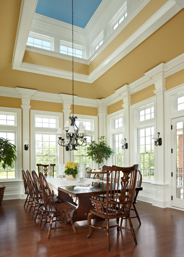 Geschlossenes, Großes Klassisches Esszimmer ohne Kamin mit gelber Wandfarbe, dunklem Holzboden und braunem Boden in Sonstige