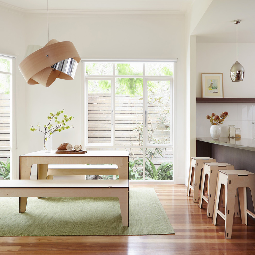 Inspiration pour une salle à manger ouverte sur la cuisine design de taille moyenne avec un mur blanc et un sol en bois brun.