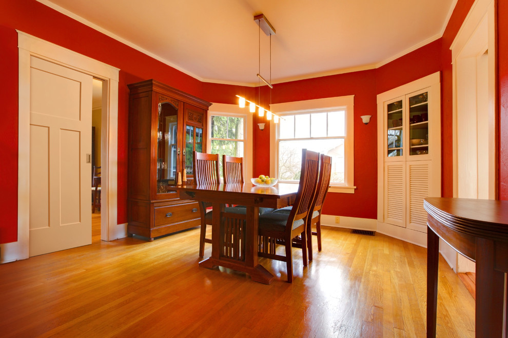 Immagine di una sala da pranzo stile americano chiusa e di medie dimensioni con pareti rosse e parquet chiaro
