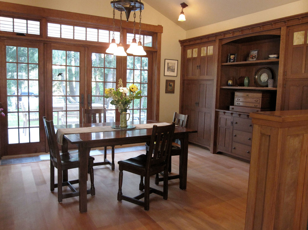 Exemple d'une salle à manger craftsman de taille moyenne avec un mur blanc, un sol en bois brun, aucune cheminée et un sol marron.