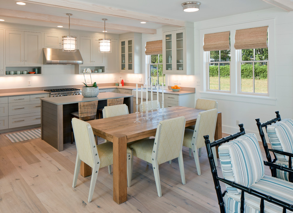 Immagine di una sala da pranzo aperta verso la cucina costiera con pareti bianche e pavimento in legno massello medio