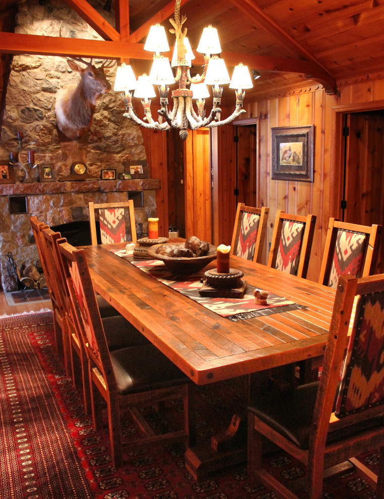 Ispirazione per una grande sala da pranzo aperta verso la cucina stile rurale con pareti multicolore, parquet chiaro, camino bifacciale e cornice del camino in pietra