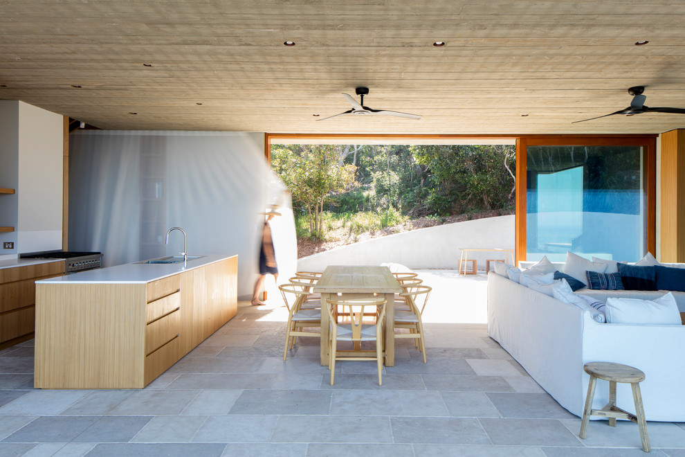 Exemple d'une salle à manger ouverte sur la cuisine bord de mer de taille moyenne avec un sol en calcaire, aucune cheminée et un sol beige.