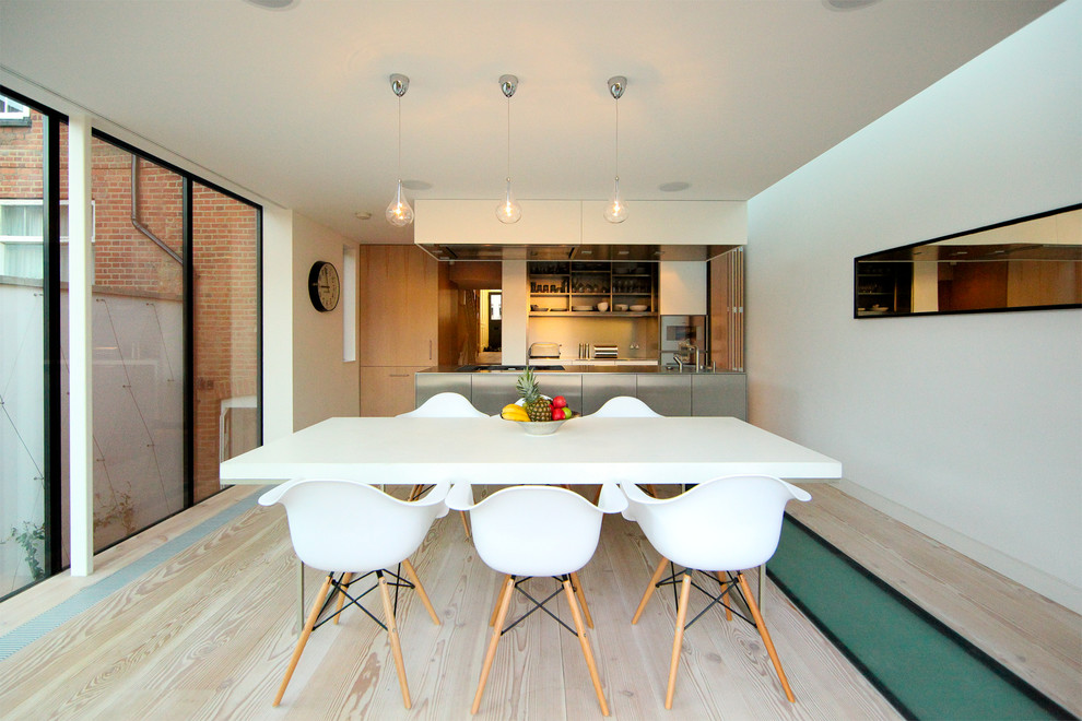 Esempio di una sala da pranzo aperta verso la cucina design con pareti bianche, parquet chiaro e nessun camino