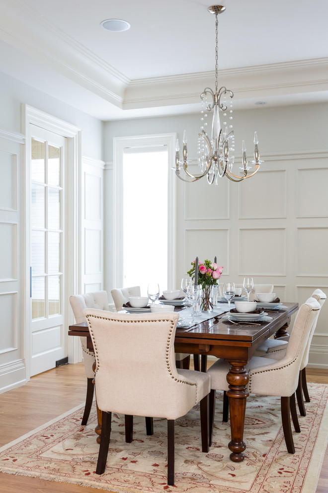 Elegant medium tone wood floor dining room photo in Toronto with white walls