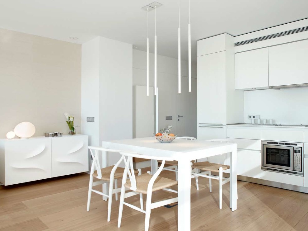 Aménagement d'une petite salle à manger ouverte sur la cuisine contemporaine avec un mur blanc, parquet clair et aucune cheminée.