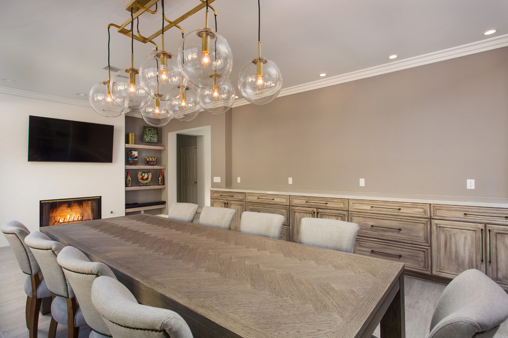 Photo of a large classic enclosed dining room in Los Angeles with beige walls, porcelain flooring, a standard fireplace, a tiled fireplace surround and grey floors.