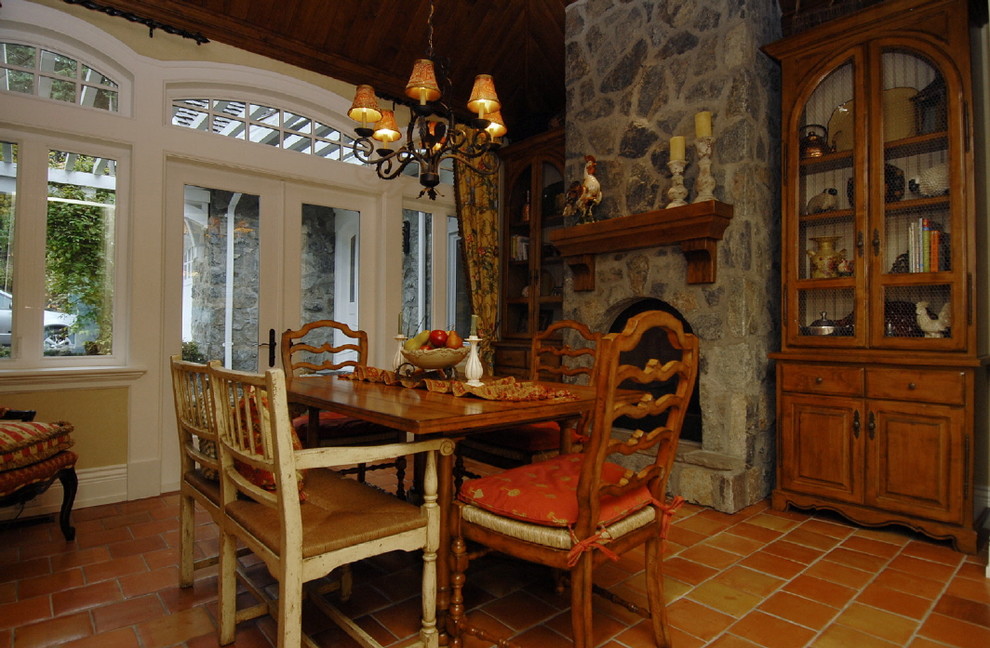 Idées déco pour une salle à manger ouverte sur la cuisine montagne de taille moyenne avec un mur beige, tomettes au sol, une cheminée standard et un manteau de cheminée en pierre.