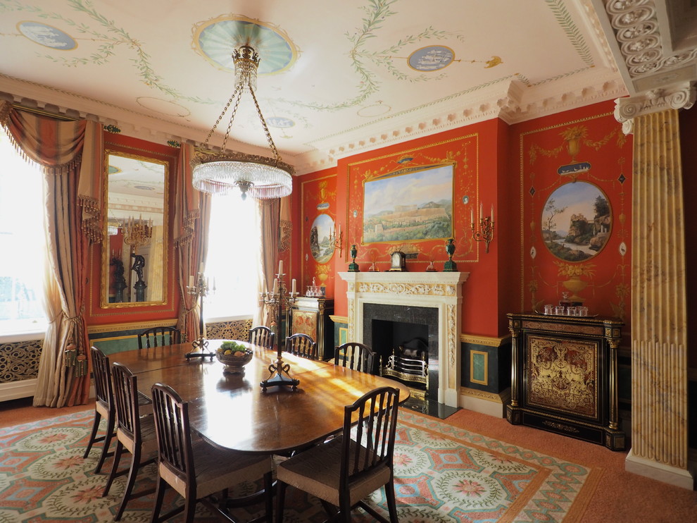 Immagine di una sala da pranzo chic di medie dimensioni con pareti rosse, camino classico, moquette e pavimento arancione