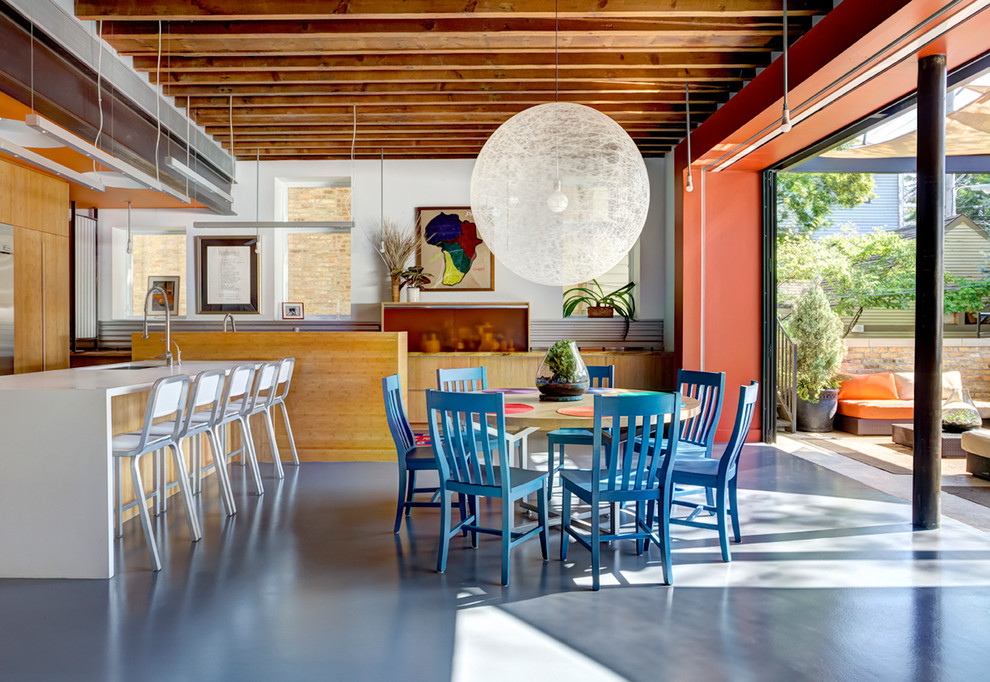 Immagine di una sala da pranzo aperta verso la cucina industriale con pareti bianche e pavimento in cemento