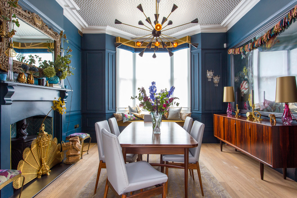 Medium sized bohemian dining room in Hertfordshire with blue walls, light hardwood flooring, a wood burning stove, a tiled fireplace surround, beige floors and feature lighting.