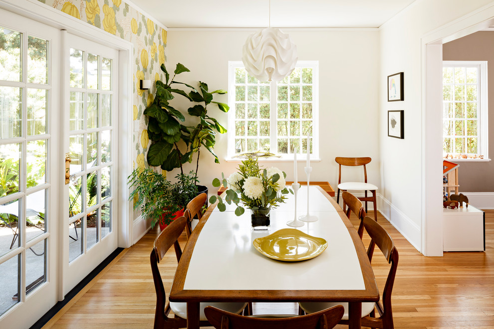 Réalisation d'une salle à manger design fermée et de taille moyenne avec un sol en bois brun et un mur blanc.