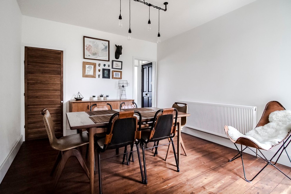 Cette image montre une salle à manger ouverte sur la cuisine nordique de taille moyenne avec un mur blanc, parquet foncé, aucune cheminée et un sol marron.