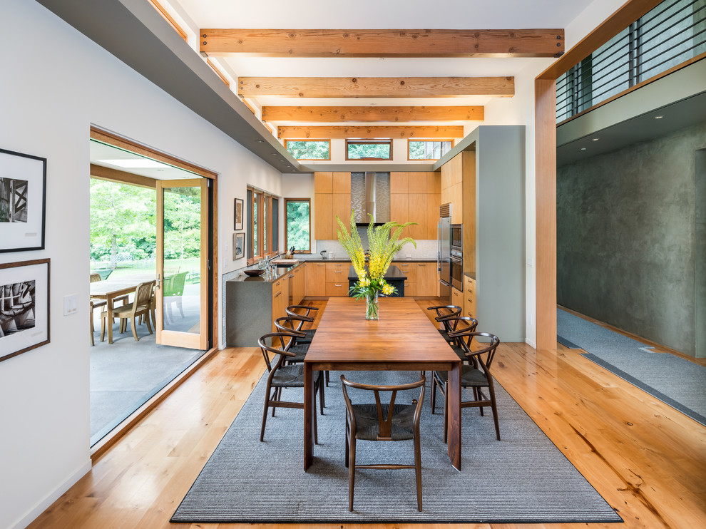 Foto di una sala da pranzo aperta verso la cucina design con pareti bianche, pavimento in legno massello medio e pavimento marrone