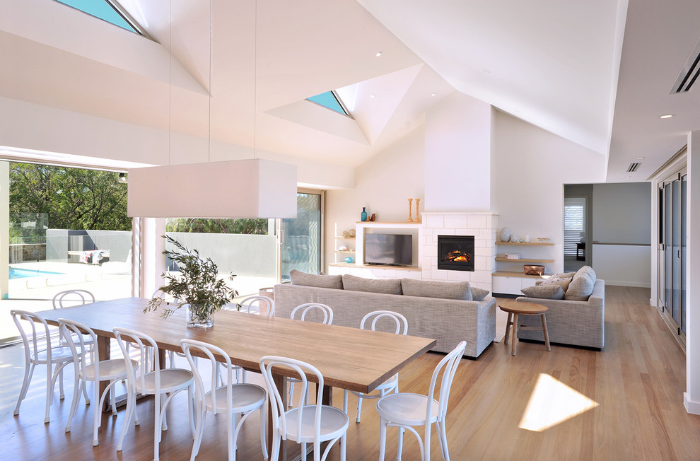 Inspiration pour une grande salle à manger ouverte sur le salon design avec un mur blanc, parquet clair, un manteau de cheminée en pierre, une cheminée standard et un sol marron.