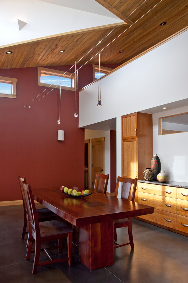 Inredning av ett modernt litet kök med matplats, med röda väggar och betonggolv