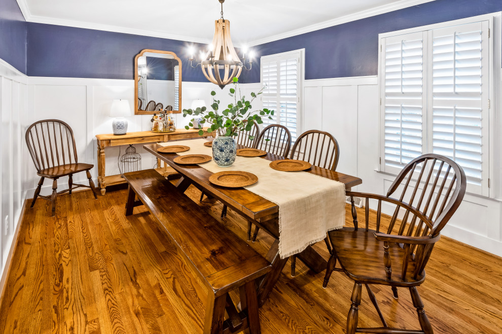 Cette photo montre une salle à manger bord de mer fermée avec un sol en bois brun, un sol marron, un mur bleu, aucune cheminée et boiseries.