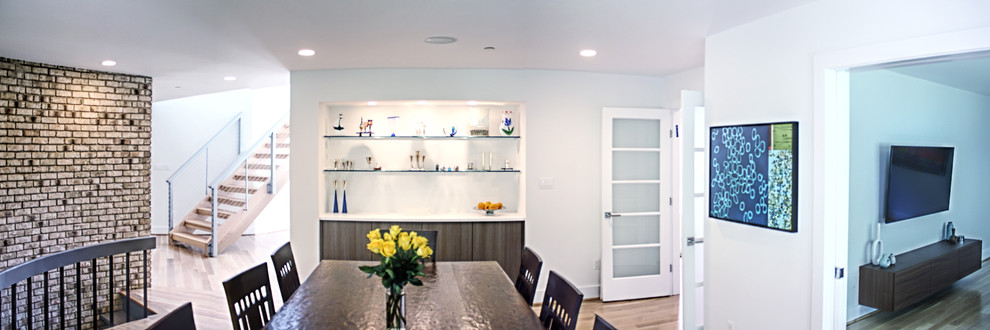 Foto di una sala da pranzo aperta verso la cucina design di medie dimensioni con pareti bianche, parquet chiaro, camino classico e cornice del camino in mattoni