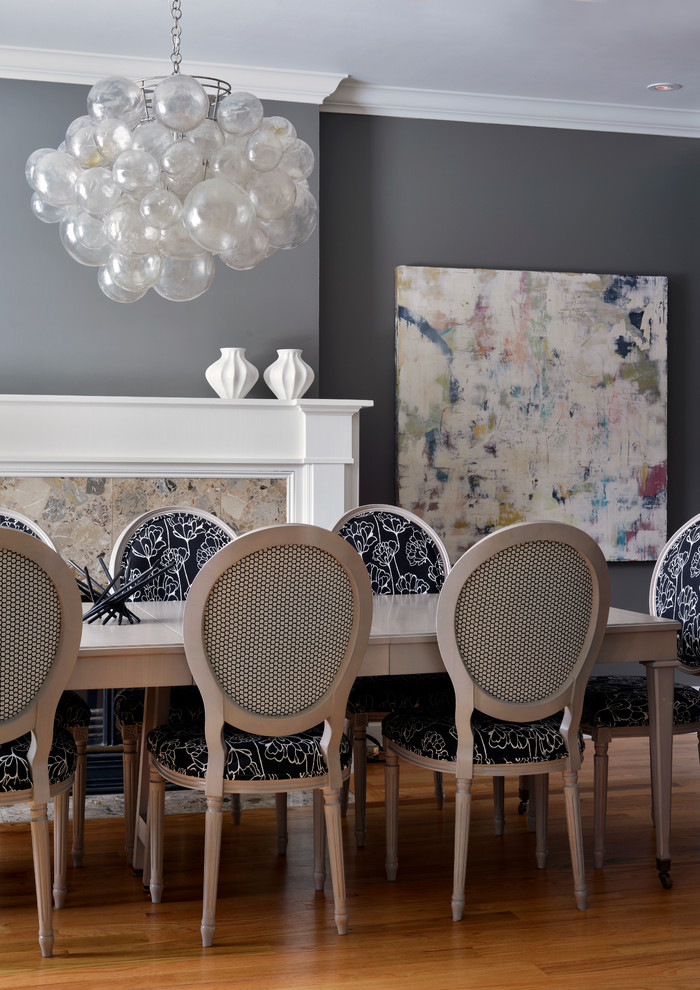 Imagen de comedor clásico renovado con paredes grises, suelo de madera en tonos medios y todas las chimeneas