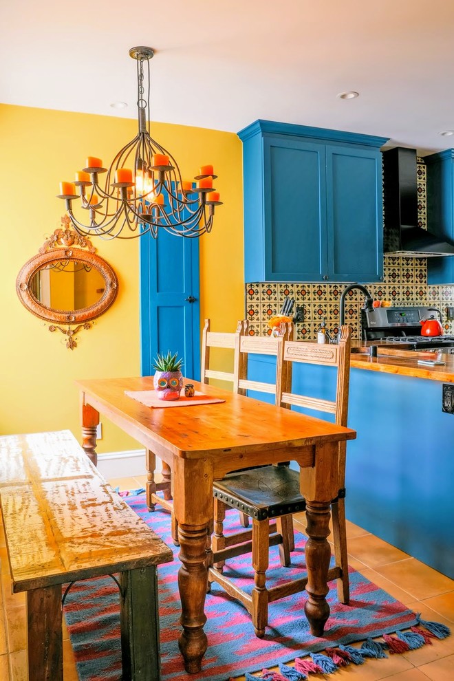 Immagine di una sala da pranzo aperta verso la cucina mediterranea con pareti gialle e pavimento in terracotta
