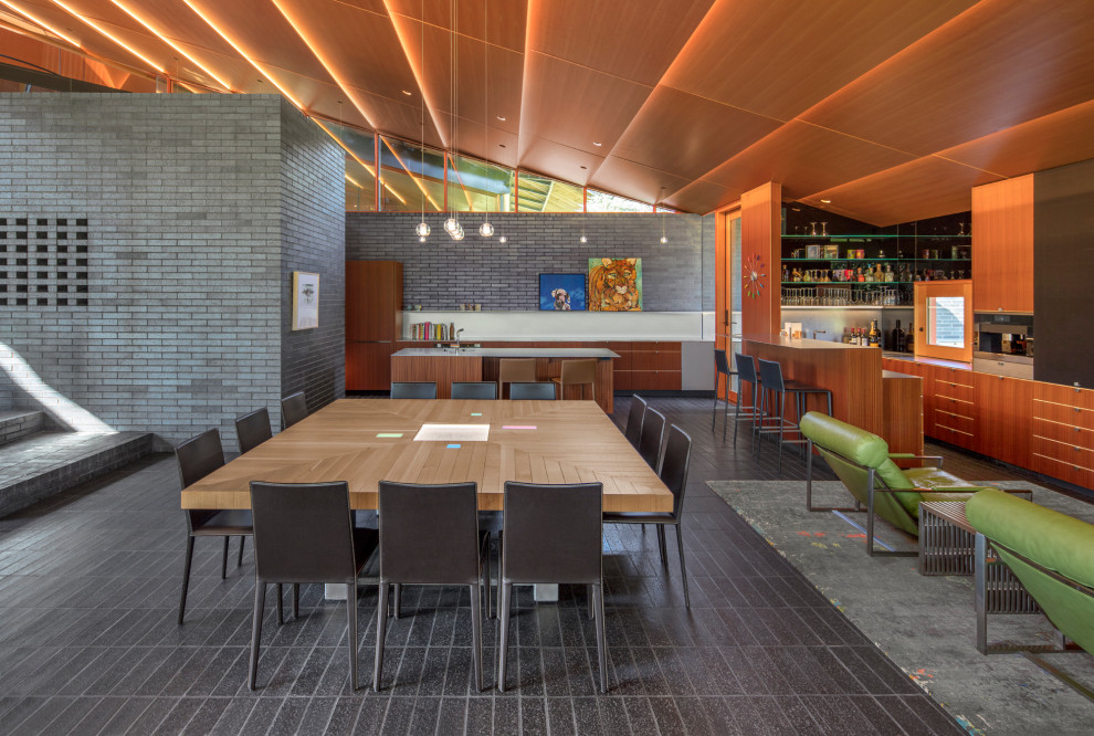 Immagine di una sala da pranzo aperta verso la cucina minimal con pareti nere e pavimento nero