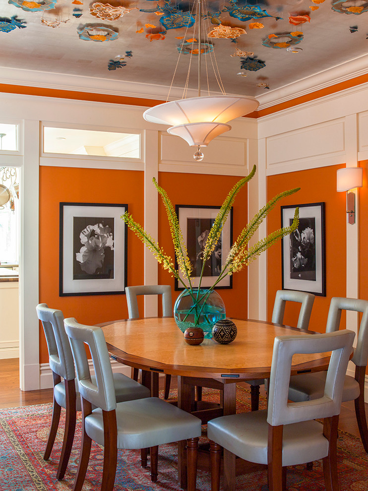 Immagine di una sala da pranzo tradizionale chiusa e di medie dimensioni con pareti arancioni, pavimento in legno massello medio e nessun camino