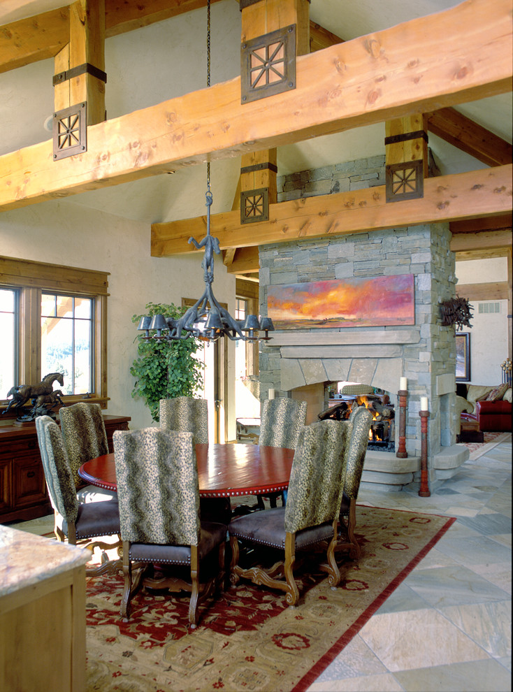 Diseño de comedor rústico grande cerrado con paredes beige, chimenea de doble cara, marco de chimenea de piedra y suelo multicolor