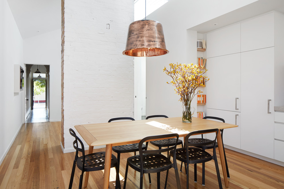 Foto di una sala da pranzo aperta verso la cucina contemporanea con pareti bianche e parquet chiaro
