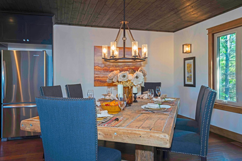 Cette image montre une salle à manger ouverte sur la cuisine chalet de taille moyenne avec un mur blanc et un sol en bois brun.