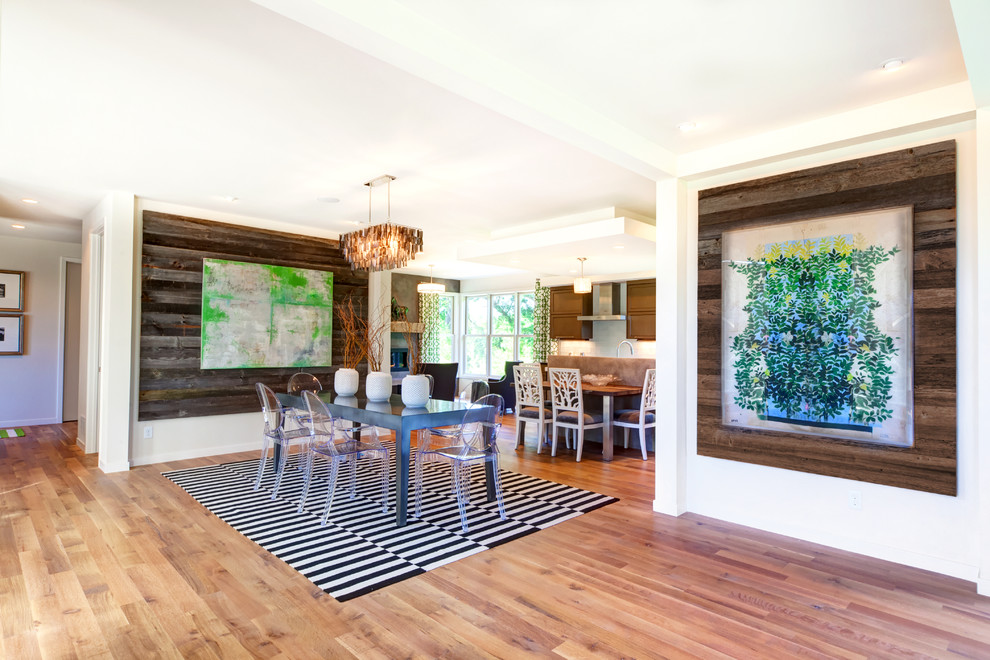 Cette photo montre une salle à manger ouverte sur la cuisine tendance avec un mur blanc et un sol en bois brun.