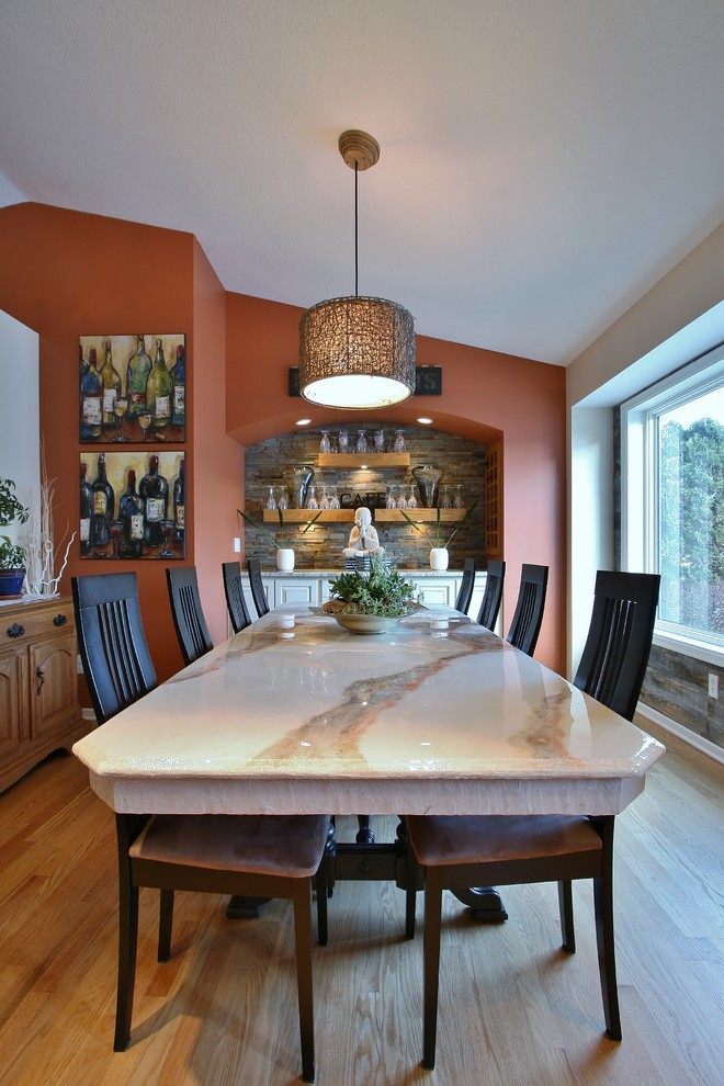 Cette image montre une salle à manger traditionnelle fermée et de taille moyenne avec un mur orange, parquet clair et aucune cheminée.