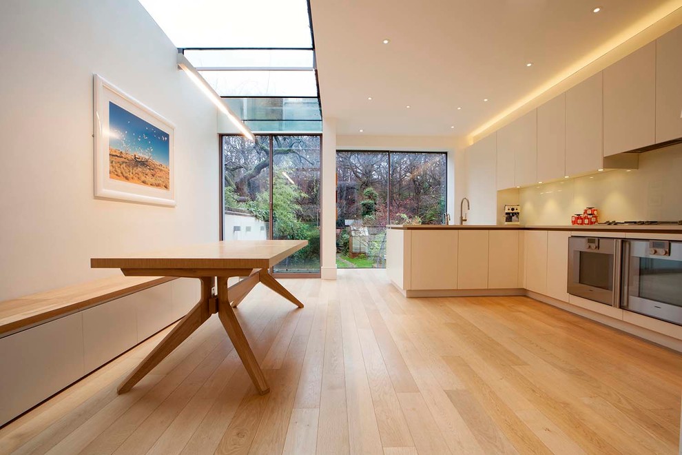 Medium sized contemporary kitchen/dining room in London with white walls, medium hardwood flooring and no fireplace.