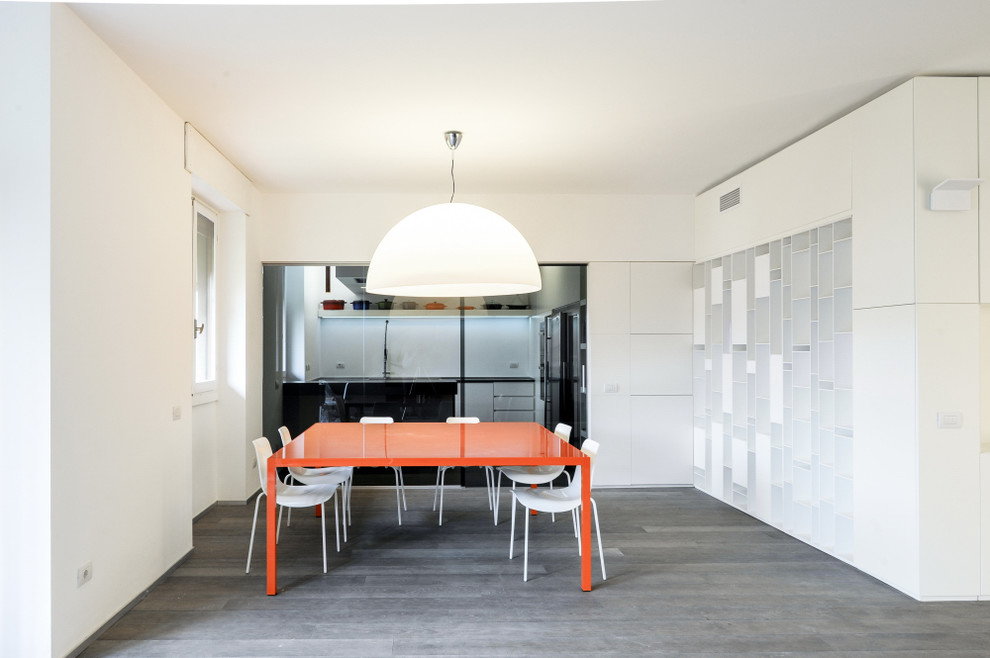 This is an example of a contemporary kitchen/dining room in Milan with white walls and dark hardwood flooring.