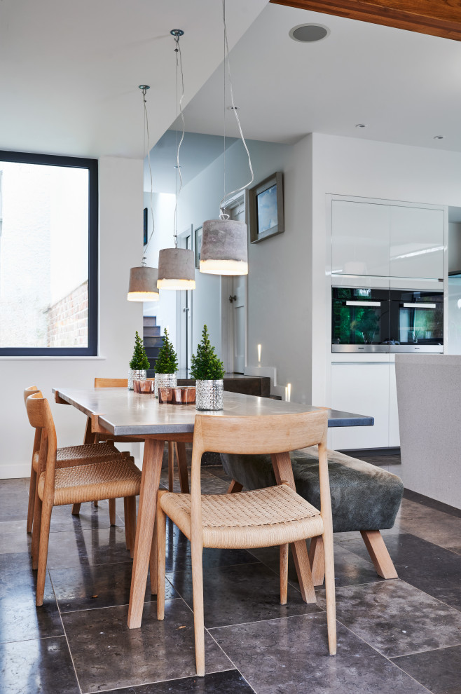 Cette image montre une salle à manger ouverte sur la cuisine design de taille moyenne avec un mur blanc et un sol gris.
