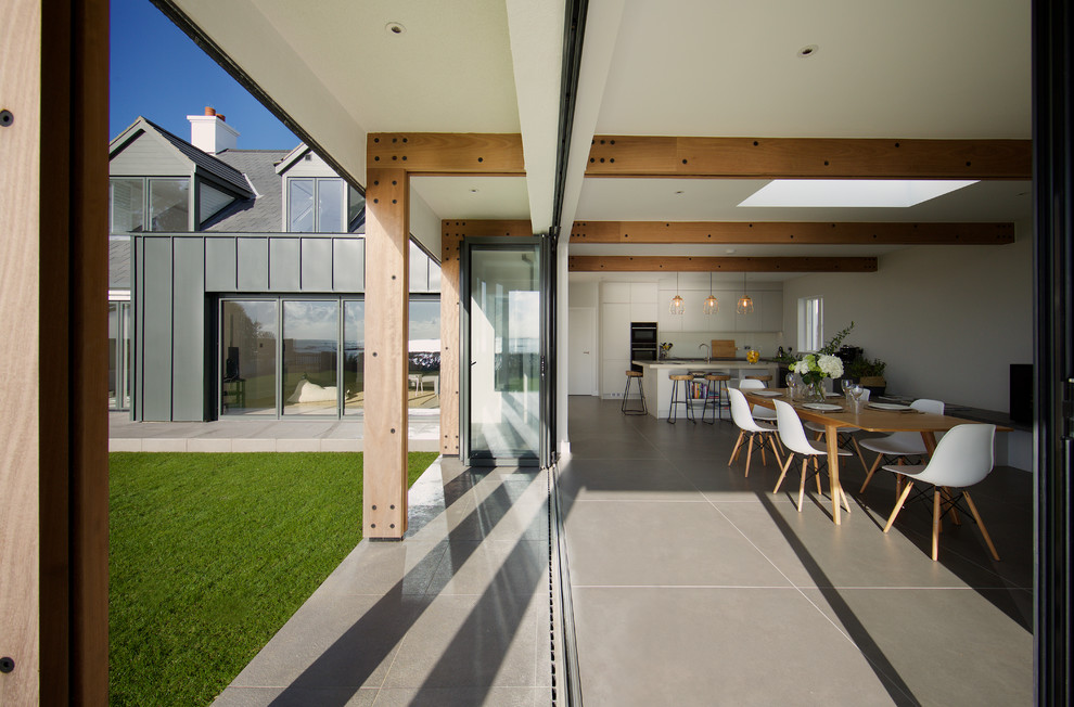Mittelgroße Moderne Wohnküche mit weißer Wandfarbe, Keramikboden, Kaminofen, Kaminumrandung aus Beton und grauem Boden in Kanalinseln