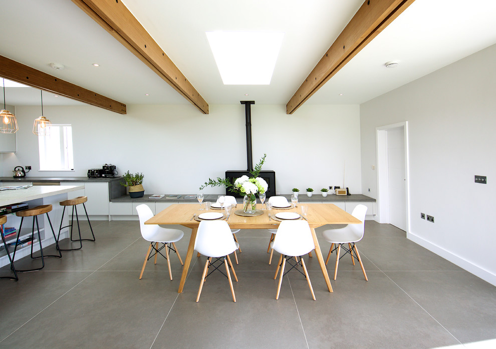 Идея дизайна: кухня-столовая среднего размера в современном стиле с белыми стенами, полом из керамической плитки, печью-буржуйкой, фасадом камина из бетона и серым полом