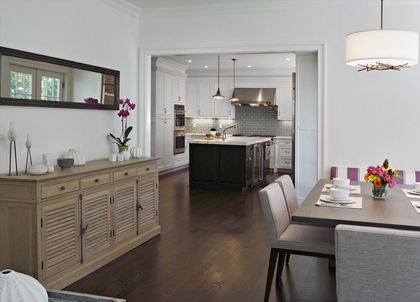 Immagine di una sala da pranzo aperta verso la cucina minimalista con pareti bianche e parquet scuro