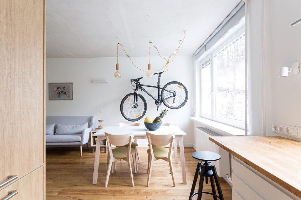 Aménagement d'une salle à manger scandinave avec un mur blanc, parquet clair et un sol marron.