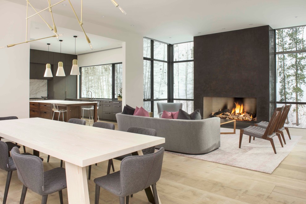 Cette photo montre une salle à manger ouverte sur la cuisine moderne de taille moyenne avec un mur blanc, parquet clair et une cheminée standard.