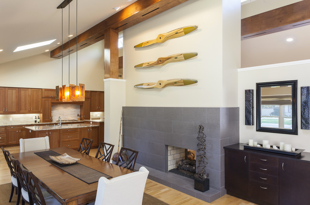 This is an example of a midcentury dining room in Detroit with a two-sided fireplace and a stone fireplace surround.