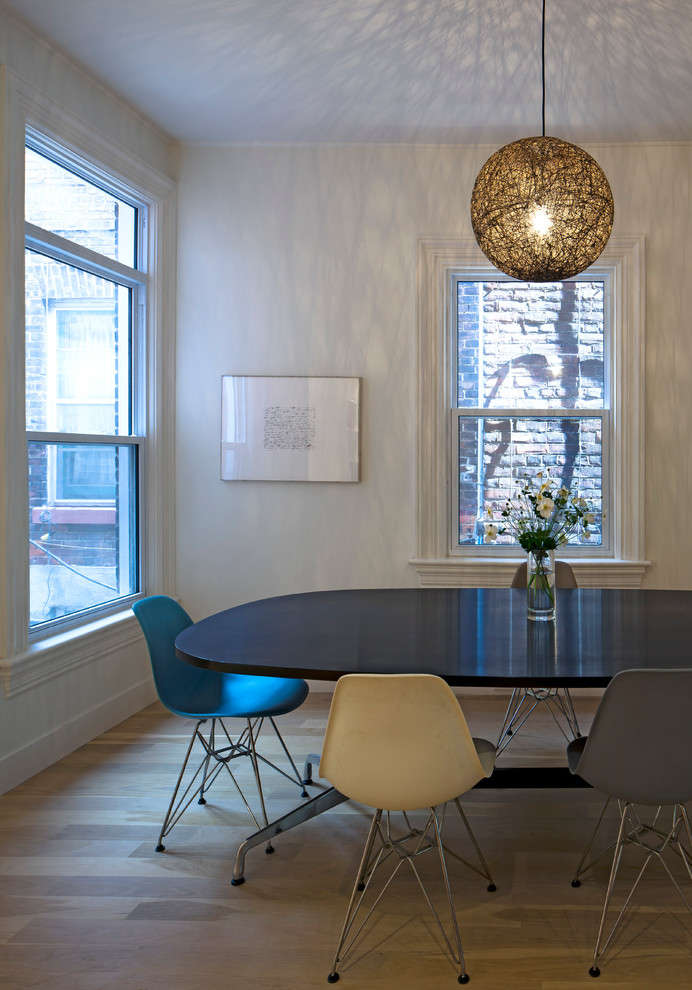 Cette image montre une salle à manger minimaliste avec un mur blanc et un sol en bois brun.