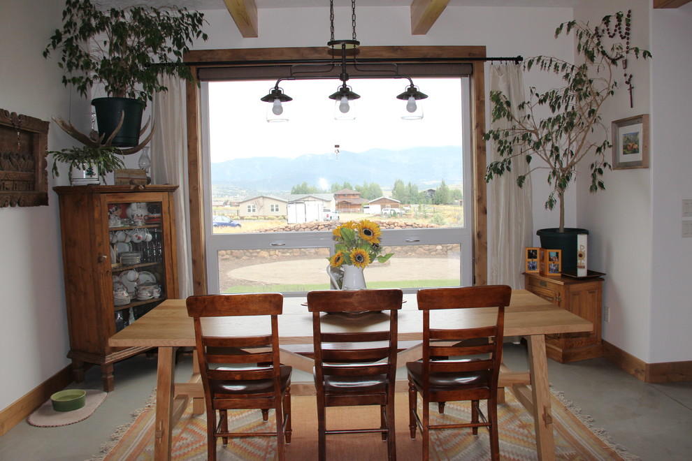 Réalisation d'une salle à manger ouverte sur le salon champêtre de taille moyenne avec un mur blanc et sol en béton ciré.