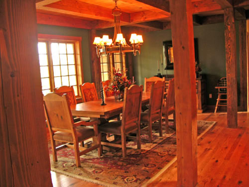 Inspiration pour une salle à manger ouverte sur le salon chalet de taille moyenne avec un mur vert, parquet foncé, une cheminée standard et un manteau de cheminée en pierre.