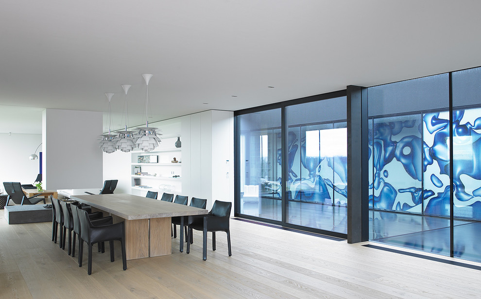 Imagen de comedor contemporáneo con paredes blancas y suelo de madera clara