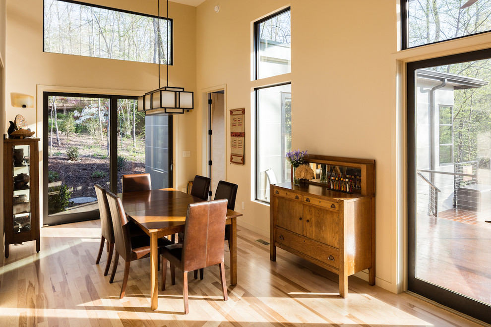 Offenes, Kleines Modernes Esszimmer mit gelber Wandfarbe und braunem Holzboden in Raleigh