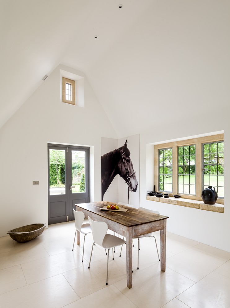 This is an example of a farmhouse enclosed dining room in Gloucestershire with white walls, limestone flooring and beige floors.