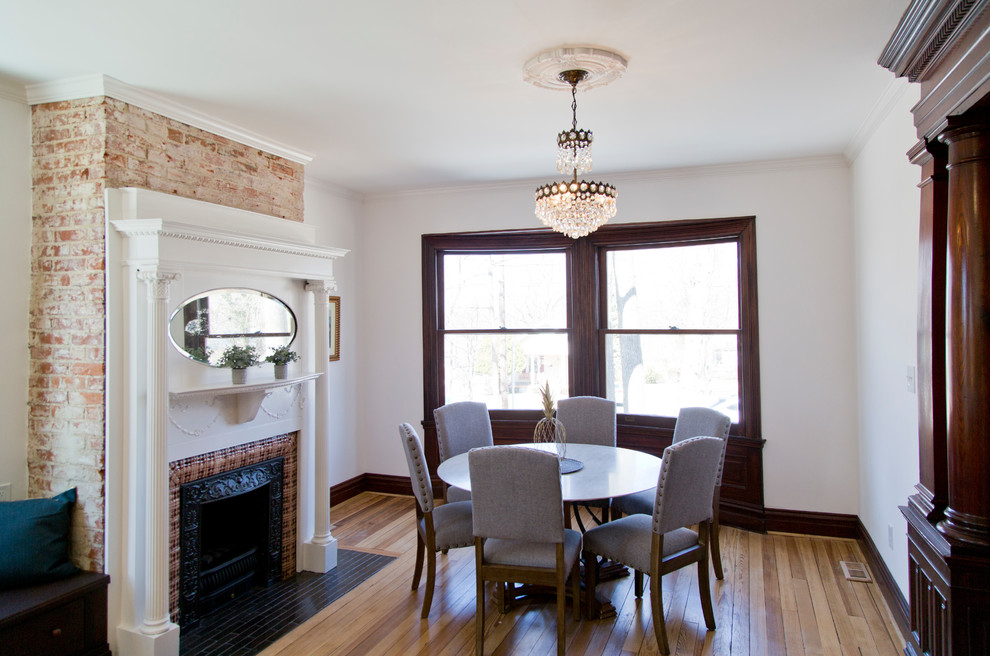 Cette image montre une très grande salle à manger ouverte sur la cuisine victorienne avec un mur blanc, un sol en bois brun, une cheminée standard et un manteau de cheminée en carrelage.