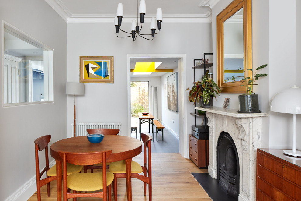 Inspiration pour une salle à manger ouverte sur le salon traditionnelle de taille moyenne avec un mur gris, parquet clair, une cheminée standard, un manteau de cheminée en pierre et un sol marron.